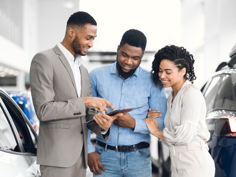 Couple looking through car options with sales representative - George Matick Chevrolet in Redford MI